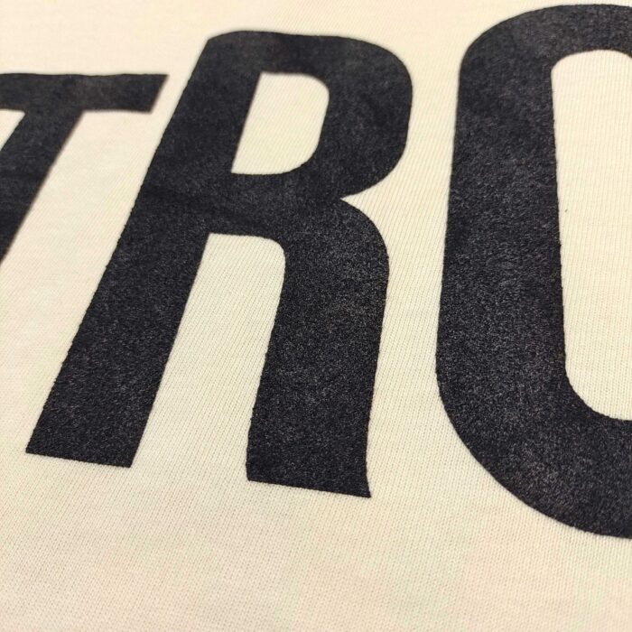 Tessuto casual con grandi lettere nere su tessuto di cotone chiaro, stile streetwear moderno.