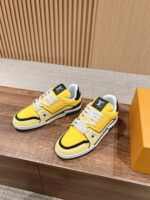 Sneaker gialle di lusso con dettagli neri e bianchi, su sfondo elegante e scatola arancione raffinata.