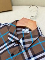 Camicia Burberry a quadri marrone su appendiabiti in legno, elegante e di alta qualità.
