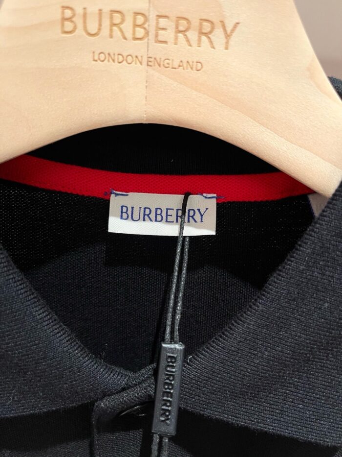 Maglietta polo nera Burberry, tag elegante e gancio di legno con logo, stile e autenticità raffinati.