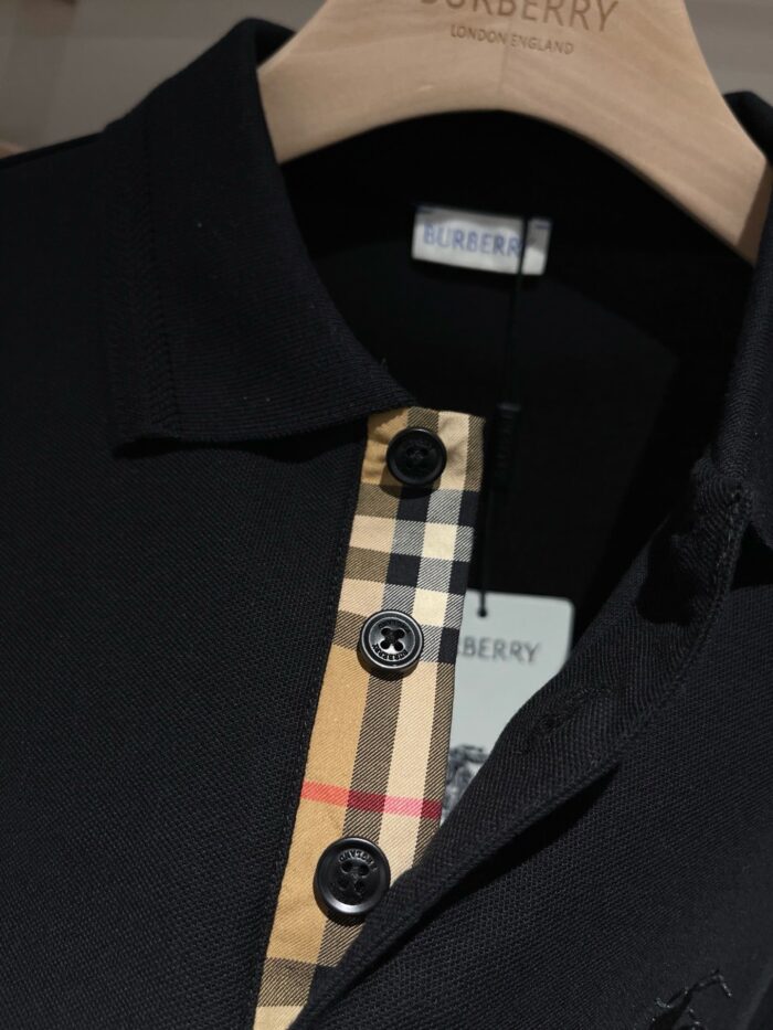Maglietta polo Burberry nera con motivo check beige e dettagli lucidi, stile elegante e casual.