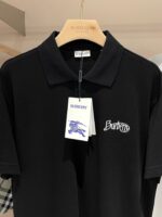 Polo nera Burberry con logo ricamato su appendiabiti in legno, stile elegante e versatile.