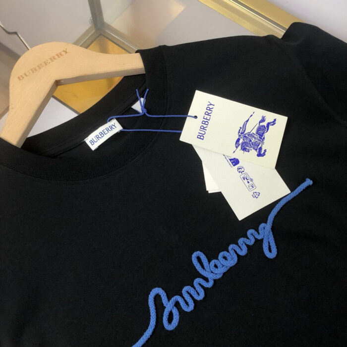 Maglietta nera Burberry con ricamo blu, dettagli eleganti e tag di alta qualità.