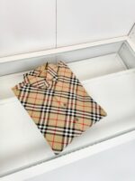 Camicia Burberry Check beige con pattern a strisce, elegante esposizione in vetrina raffinata.