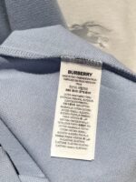 Etichetta Burberry su maglietta blu di alta qualità, dettagli di cura e composizione.