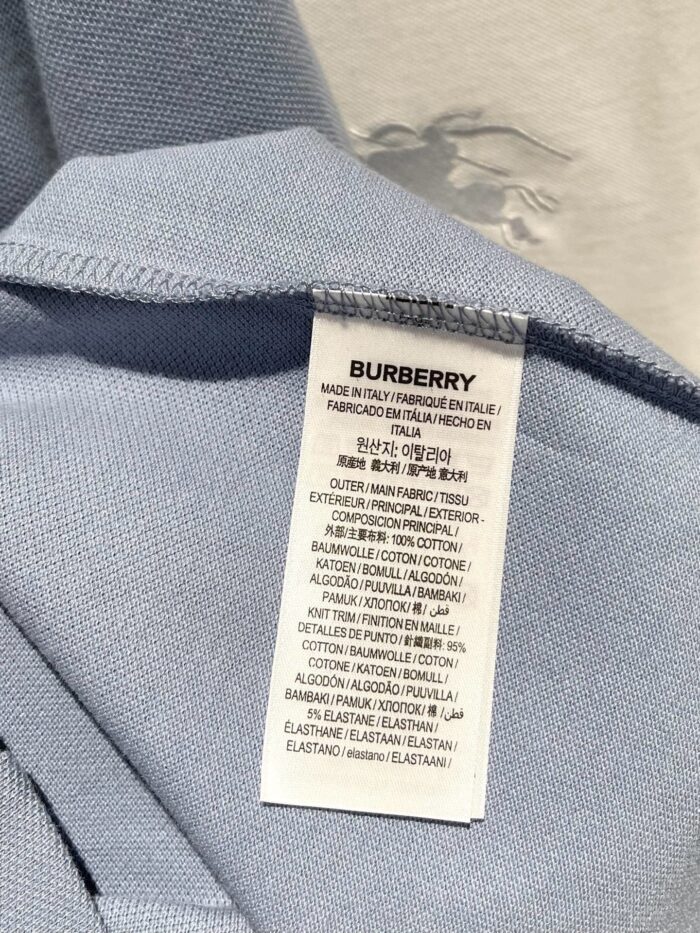 Etichetta Burberry su maglietta blu di alta qualità, dettagli di cura e composizione.