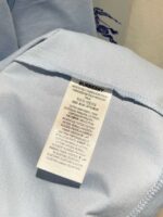 Etichetta Burberry su abbigliamento celeste con istruzioni di cura e logo elegante.