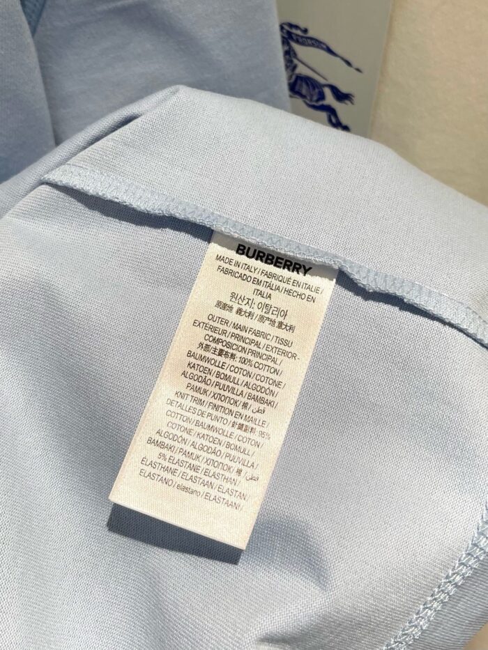 Etichetta Burberry su abbigliamento celeste con istruzioni di cura e logo elegante.