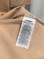 Etichetta originale Burberry in tessuto beige con logo nero e istruzioni di cura.