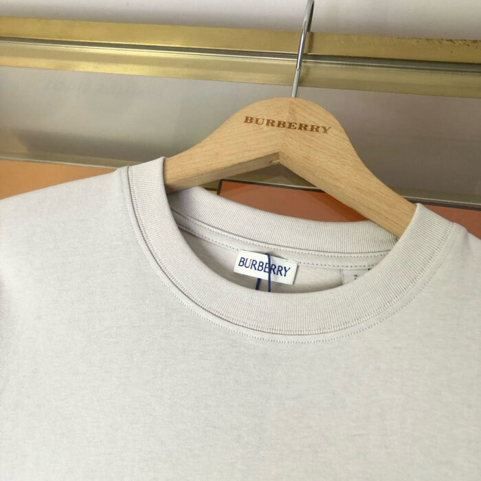 Maglione Burberry crema su appendiabiti di legno elegante, stile luxury e design raffinato.
