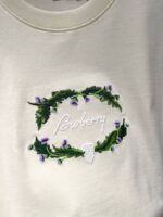 Felpa Burberry con ricamo floreale verde e viola su tessuto morbido e elegante.