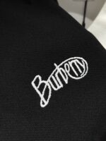 Logo Burberry ricamato nero e bianco su abbigliamento di lusso elegante.