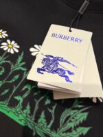 Etichetta Burberry con fiore, cavaliere blu e dettagli eleganti su tessuto nero.