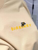 Maglione Burberry con logo giallo e disegno di ape giocosa, stile moderno e accattivante.