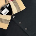 Polo Burberry nera con colletto check beige, tessuto testurizzato e bottoni eleganti.