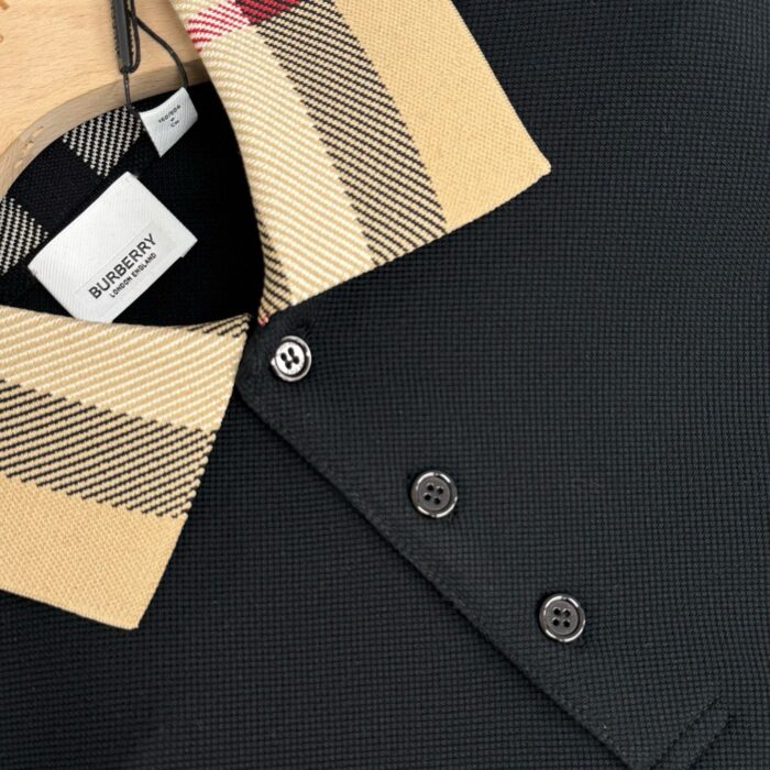 Polo Burberry nera con colletto check beige, tessuto testurizzato e bottoni eleganti.