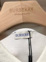 Etichetta Burberry e appendiabiti in legno, simbolo di eleganza e tradizione di lusso inglese.