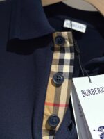 Polo Burberry Navy con colletto tartan beige e dettagli eleganti, stile classico e sofisticato.