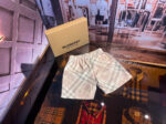 Shorts Burberry Tartan di lusso su superficie riflettente in boutique, confezione premium.