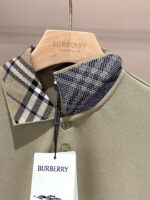 Polo Burberry beige con colletto a fantasia e dettagli di alta qualità, su appendiabiti di legno.