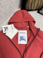Giacca rossa Burberry moderna con etichette di lusso, stile elegante e vibrante.
