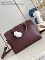 Borsa in pelle bordeaux con dettagli floreali, manici eleganti e elemento decorativo con nastro bianco.