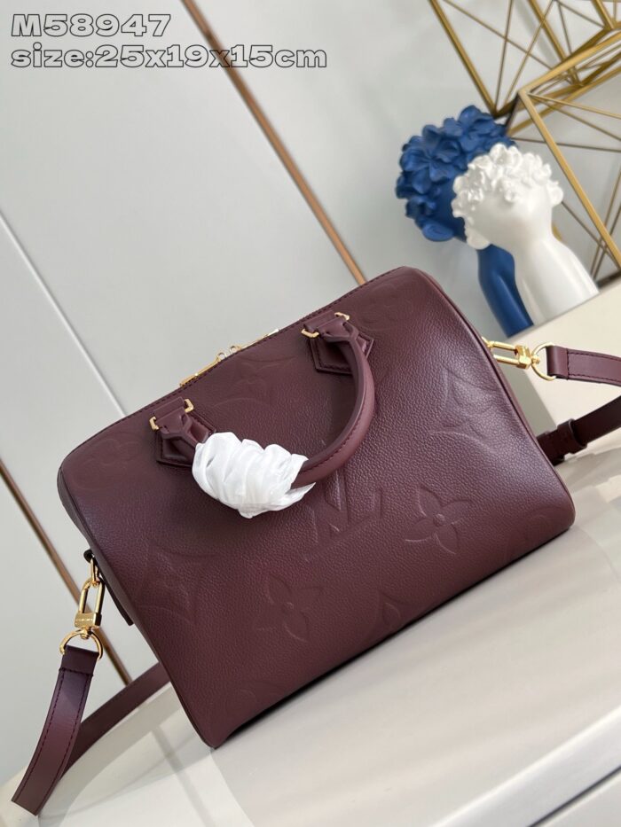 Borsa in pelle bordeaux con dettagli floreali, manici eleganti e elemento decorativo con nastro bianco.