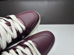 Sneakers burgundy eleganti in pelle con lacci bianchi, stile moderno e di tendenza.