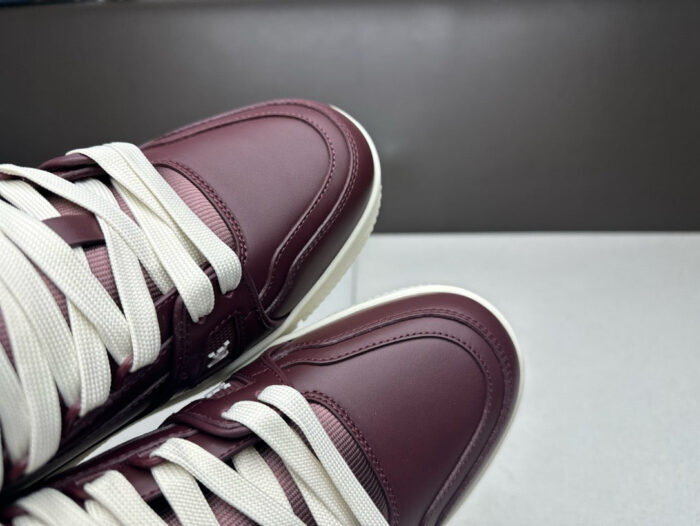 Sneakers burgundy eleganti in pelle con lacci bianchi, stile moderno e di tendenza.
