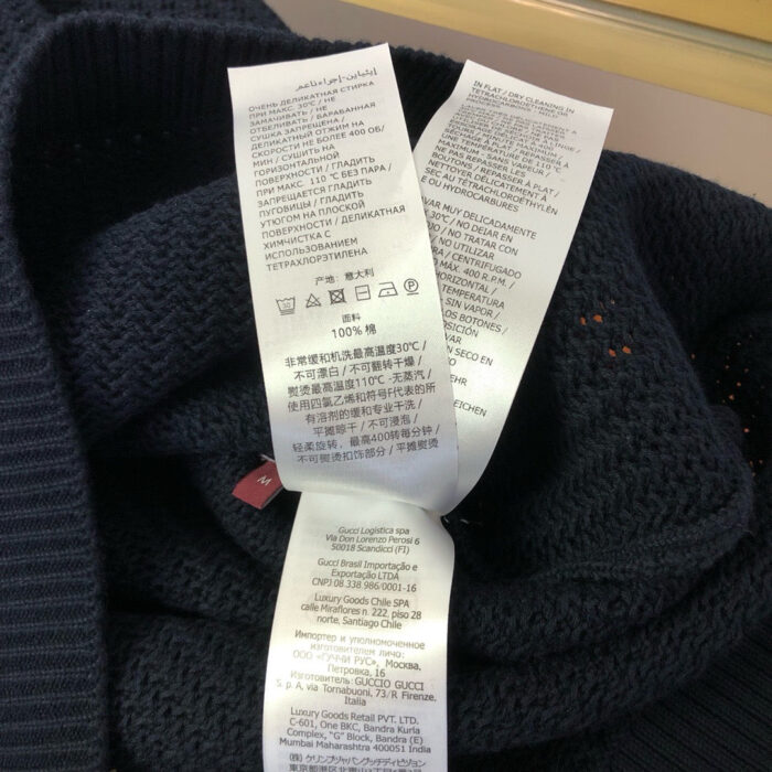 Etichette di cura su maglione navy in lana, istruzioni lavaggio e manutenzione.