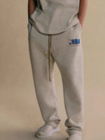 Completo athleisure con pantaloni NBA, t-shirt oversized e slip-on comodi, stile casual e confortevole.