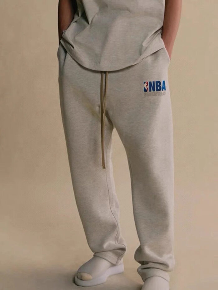 Completo athleisure con pantaloni NBA, t-shirt oversized e slip-on comodi, stile casual e confortevole.