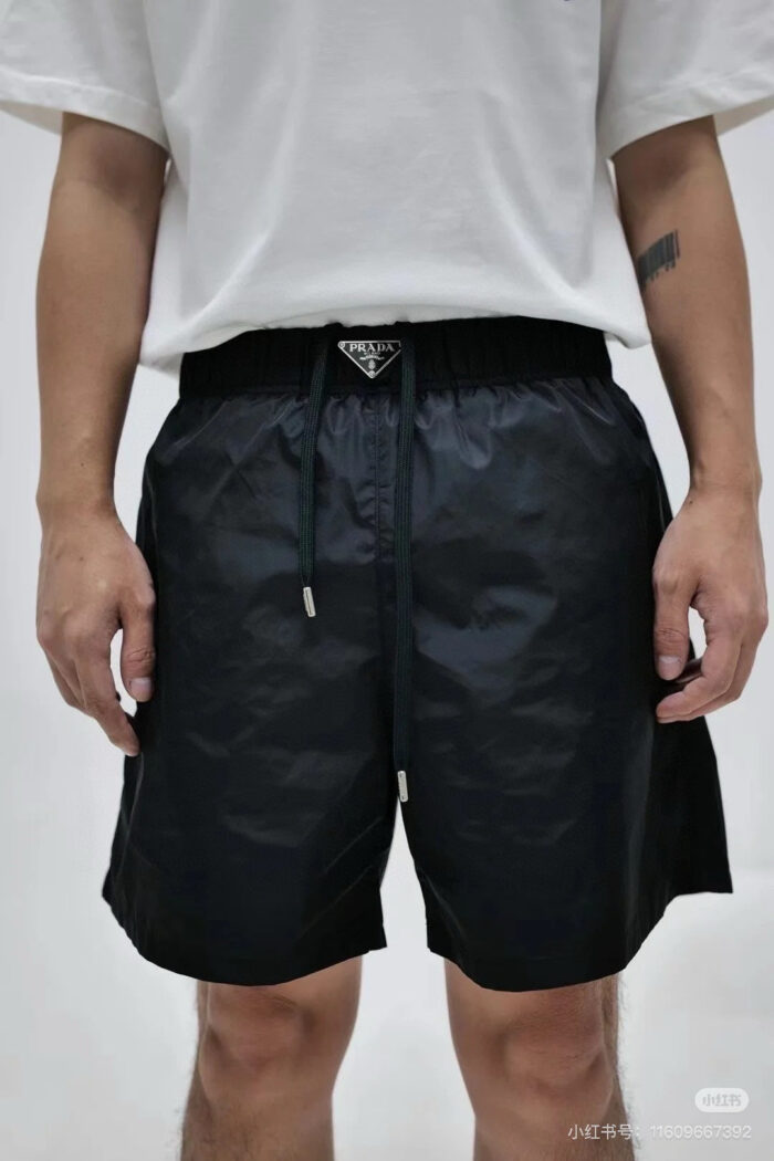 Abbigliamento casual sportivo con shorts neri, t-shirt bianca e tatuaggio visibile.