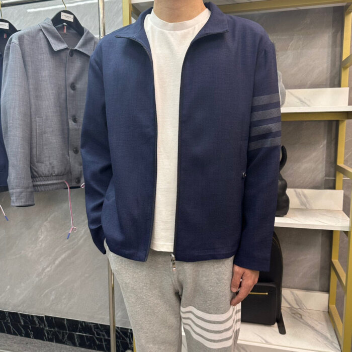 Stiloso outfit casual con giacca navy, t-shirt bianco e sweatpants grigi con righe biane.