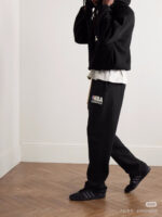 Stile streetwear casual con felpa NBA, pantaloni larghi e sneakers nere in ambienti moderni.