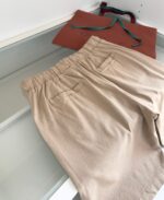 Pantaloni beige casual con borsa in pelle e dettagli colorati, stile moderno e confortevole.