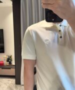 Selfie in ambiente moderno con polo beige e bottiglie di pregio, atmosfera elegante e rilassata.