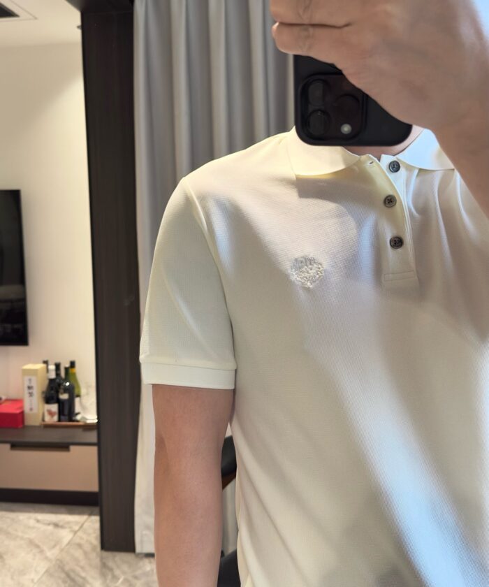Selfie in ambiente moderno con polo beige e bottiglie di pregio, atmosfera elegante e rilassata.