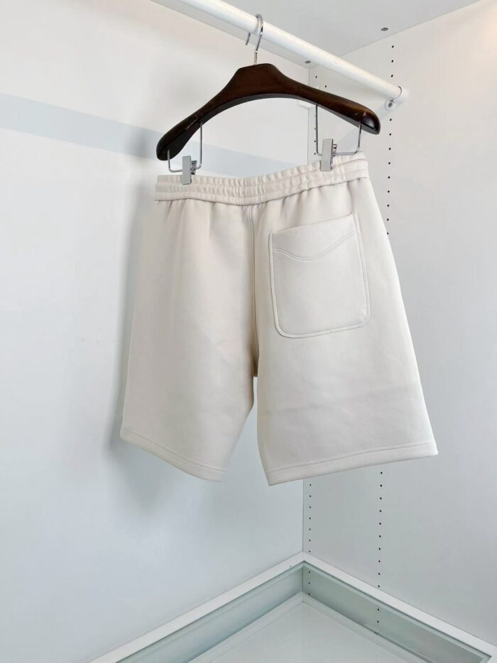 Pantaloncini bianchi casual su appendino in ambiente minimalista e moderno.