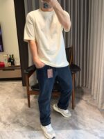Stile casual con t-shirt oversize, jeans scuri e sneakers chunky in ambiente domestico.