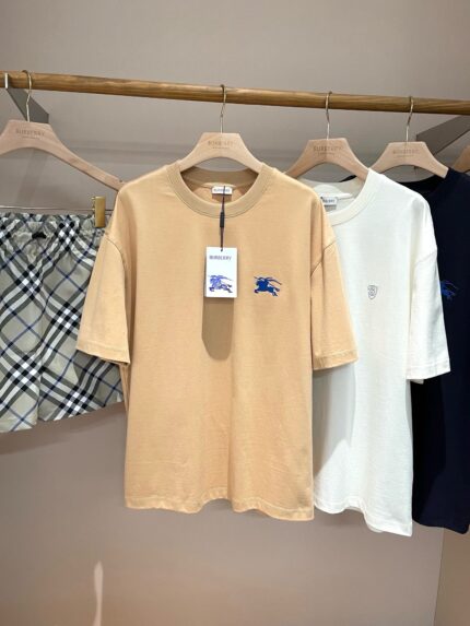Display di t-shirt minimaliste beige, bianca, blu navy e shorts a quadri grigi e neri