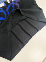 Dettaglio di orlo nero con cuciture e colori vivaci su t-shirt casual.