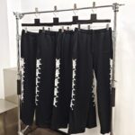 Pantaloni sportivi neri con dettagli bianchi, stile moderno e casual, su espositore minimal in boutique.