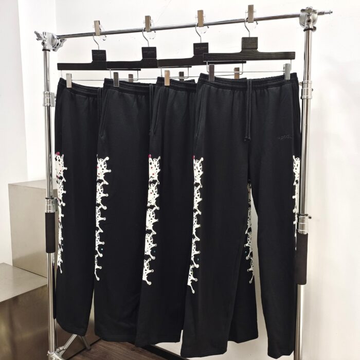Pantaloni sportivi neri con dettagli bianchi, stile moderno e casual, su espositore minimal in boutique.