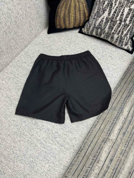 Pantaloncini neri casual su divano elegante con cuscini decorativi e stile accogliente.