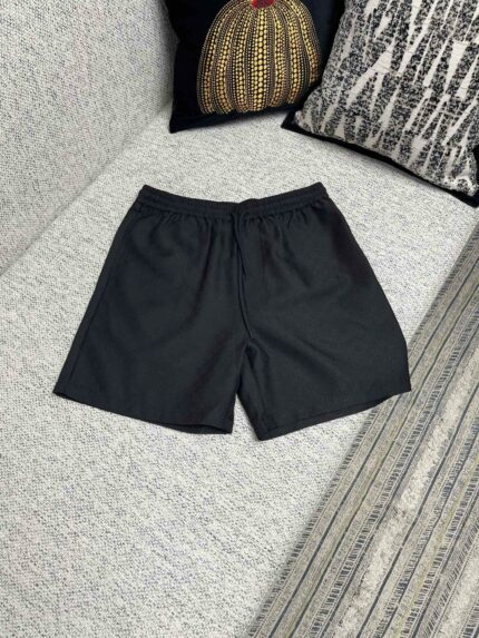 Shorts neri casual, comodi e moderni su divano grigio, perfetti per relax e sport.