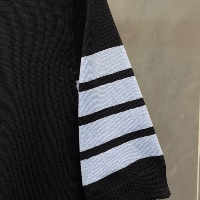 Maglione nero con dettagli a righe blu sulla manica, stile sportivo e moderno.