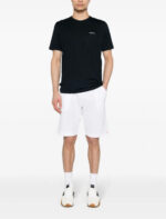 Look casual con t-shirt nera, shorts bianchi e sneakers sportive per il tempo libero.