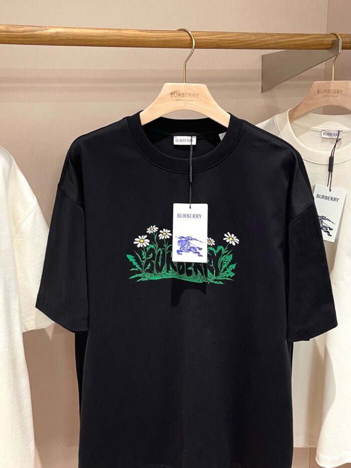 Maglietta nera casual con design floreale e foglie verdi, perfetta per uno stile fresco e giovane.