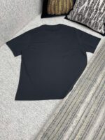 Maglietta navy casual su superficie morbida con cuscini e tessuto a righe.